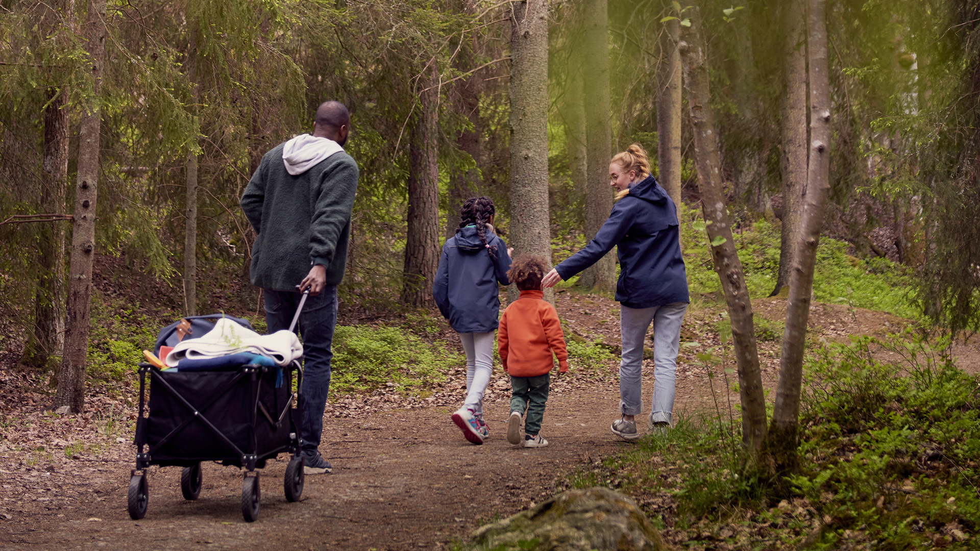 Fotograf: Maskot Bildbyrå
Bildbyrå: Johnér Familj med två barn promenerar i skogen och drar en campingvagn efter sig. Sverige.