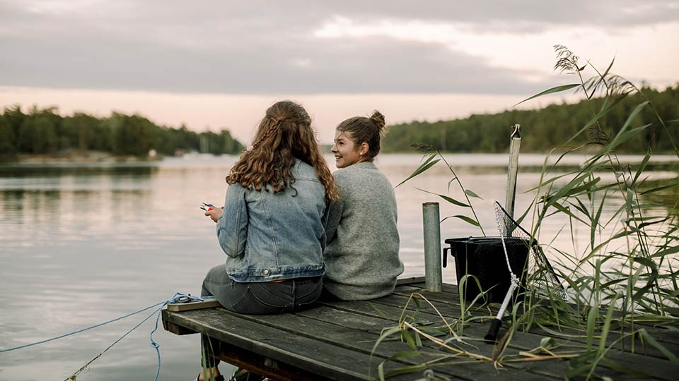 Fotograf: Maskot
Bildbyrå: Johnér Två ungdomar sitter på en brygga vid en sjö