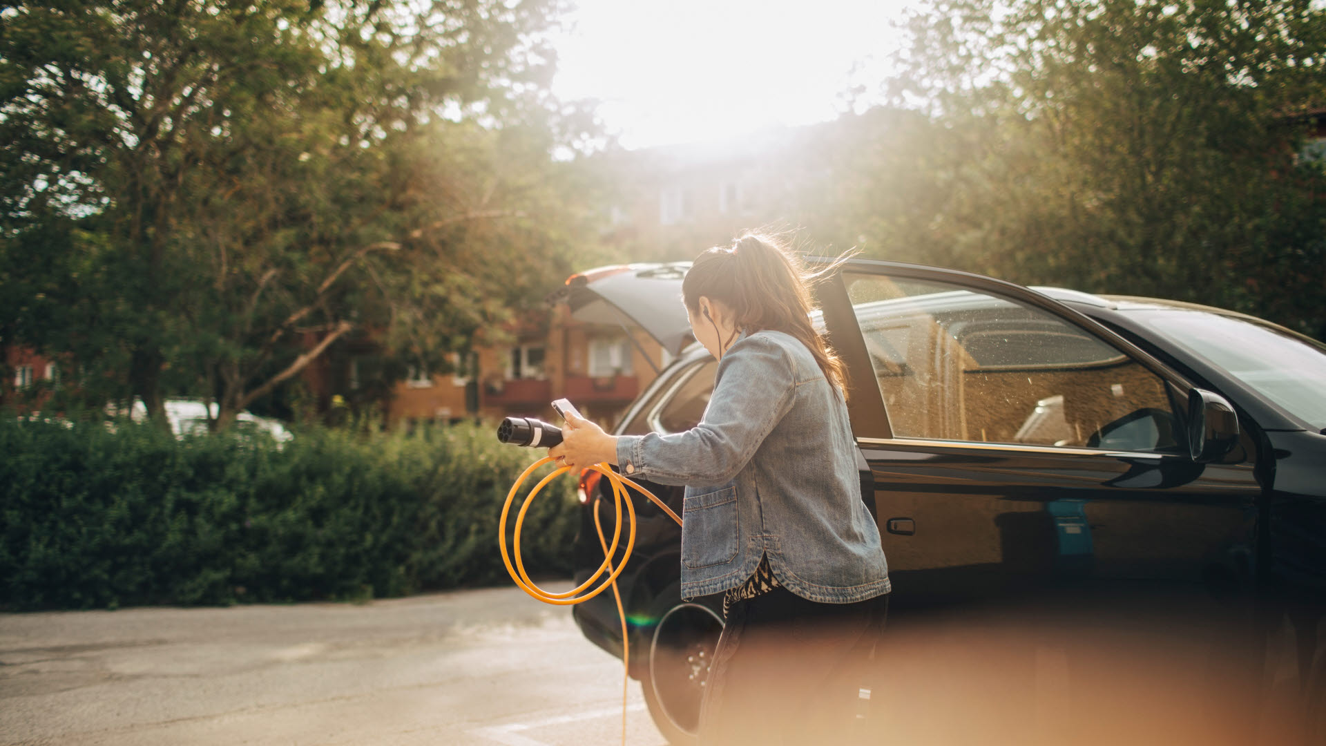 Kvinna som ska ladda sin elbil vid garageuppfart