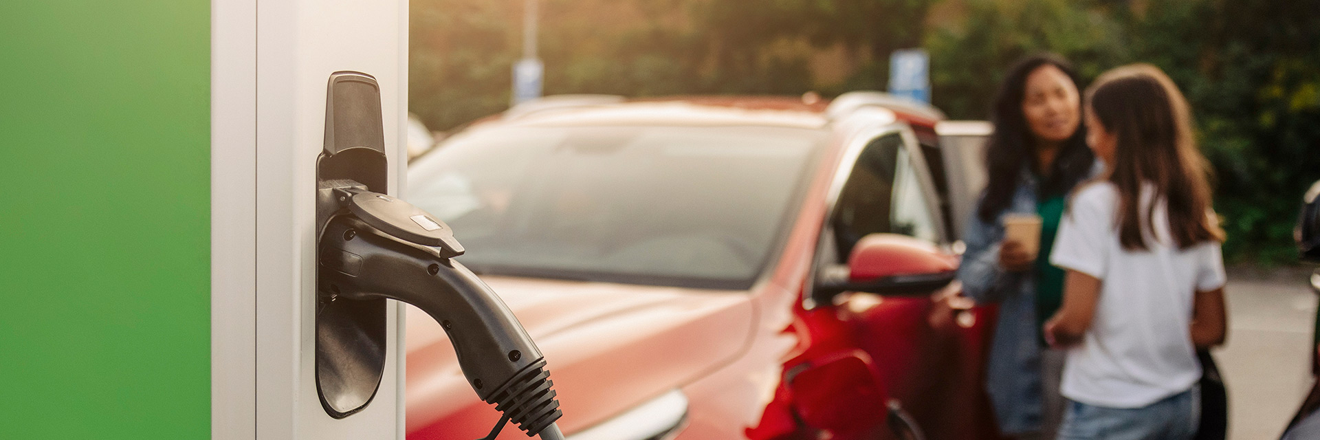 Mamma pratar med dotter på laddningsstation för elbil medan bilen laddas, Stockholm