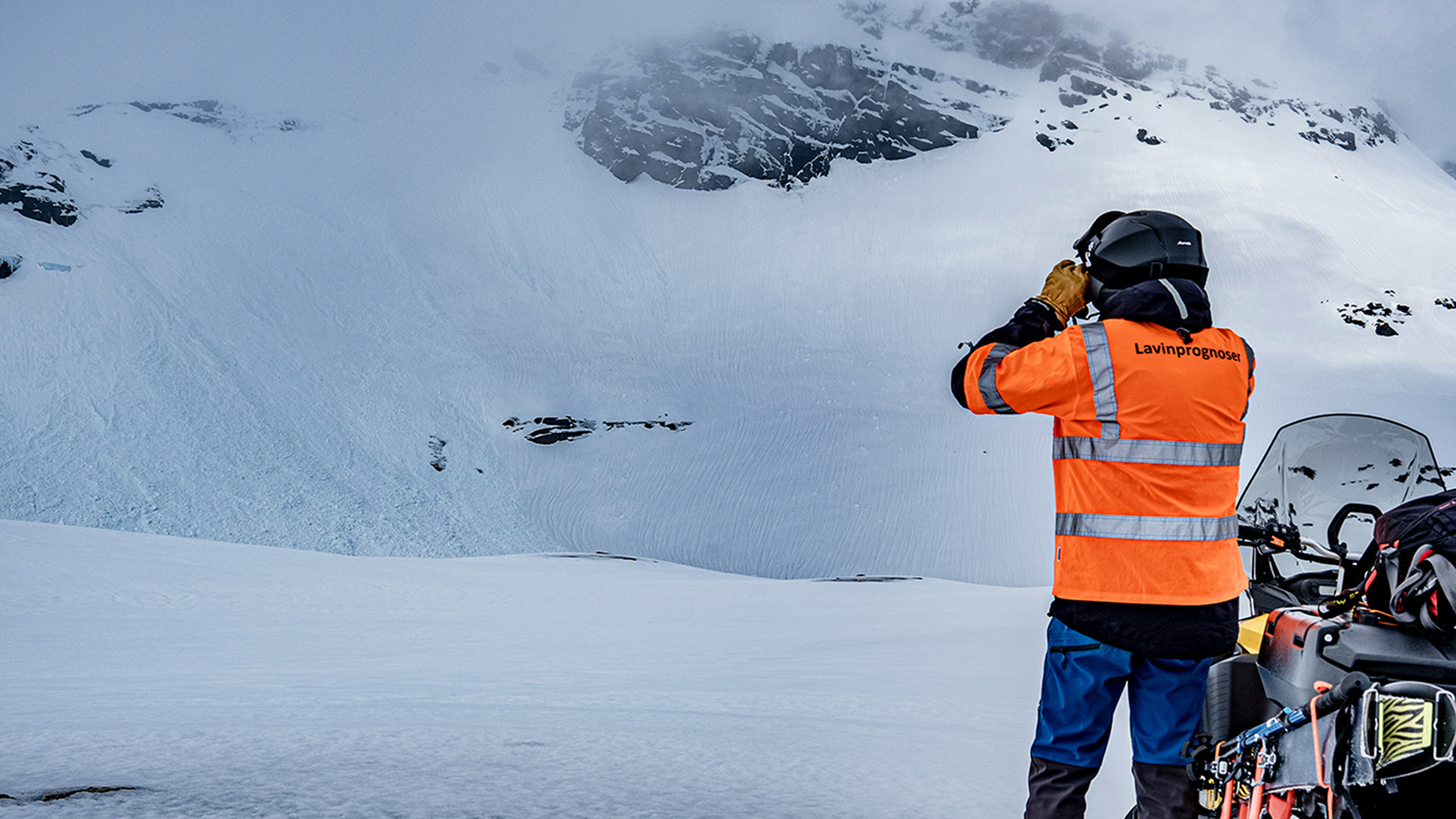 Fotograf: Sam Hedman Man bredvid skoter kikar upp på fjäll