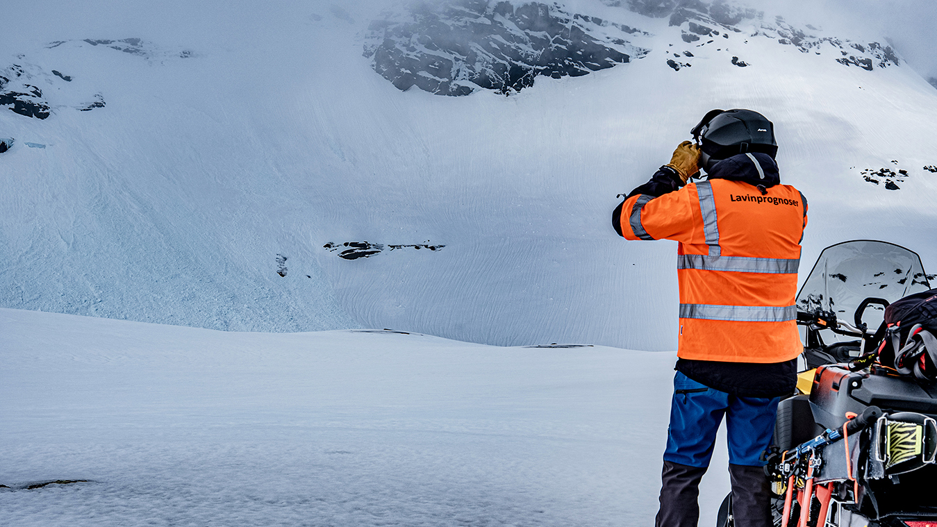 Fotograf: Sam Hedman Man bredvid skoter kikar upp på fjäll